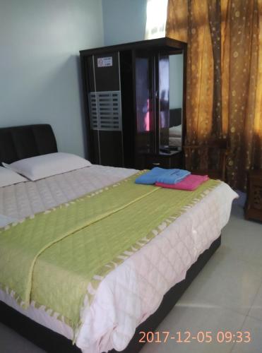 1 dormitorio con 1 cama grande con sábanas verdes y blancas en Penginapan MyCJ - Roomstay, en Kuala Terengganu