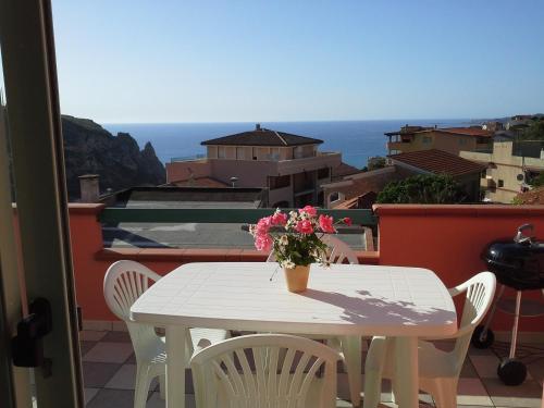 a white table with a vase of flowers on a balcony at Appartamento Elegante E Panoramico Con Splendida Vista Mare in Buggerru