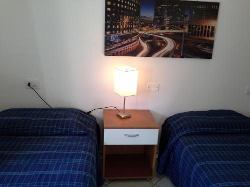 a room with two beds and a lamp on a night stand at Appartamento Elegante E Panoramico Con Splendida Vista Mare in Buggerru
