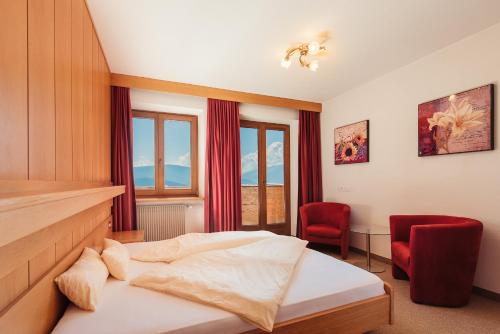 a bedroom with a bed and two red chairs at Pension Wiesenrain in Maranza