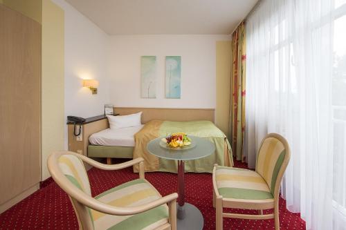 バート・フュッシンクにあるJohannesbad Hotel Phönixのベッドとテーブルと椅子のあるホテルの部屋