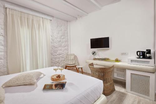 a white room with a bed and a table with wine glasses at Petri Suites in Perivolos