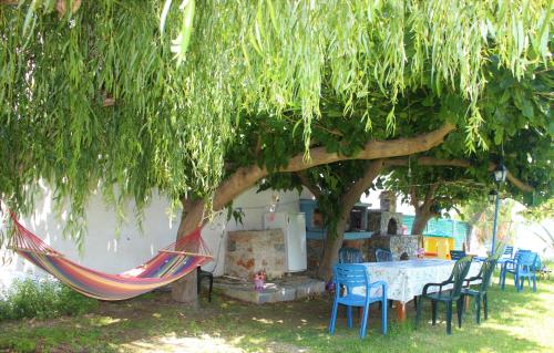 a hammock under a tree with a table and chairs at Maria's Apartments in Kalyves