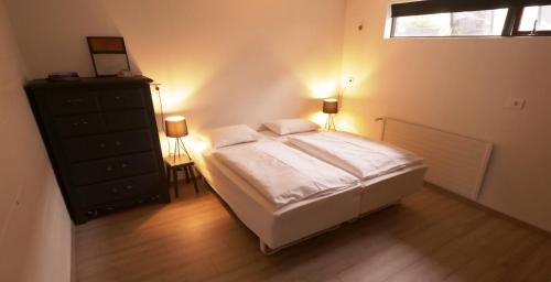 a bedroom with a bed and a dresser and a window at Manahlid Apartment in Akureyri