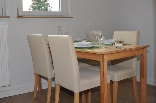 a dining room table with white chairs and a wooden table at Landhaus Bruckner in Bad Alexandersbad