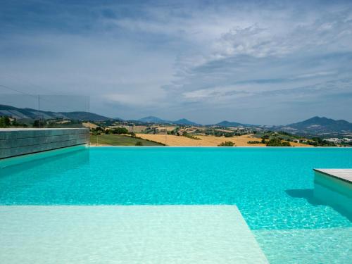 a blue swimming pool with a view of the mountains at Serre Alte Landscape Luxury Rooms in Matelica