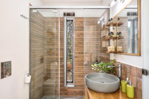 a bathroom with a sink and a glass shower at Olive Lemon Biophilic House & Lush Forest Garden in Vamos