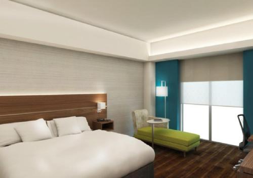 a hotel room with a bed and a green chair at Holiday Inn Express Villahermosa by IHG in Villahermosa