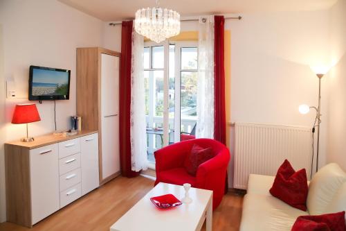 キュールングスボルンにあるStrandschlösschen Appartement 19のリビングルーム(赤い椅子、テレビ付)
