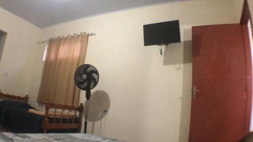 1 dormitorio con ventilador y TV en la pared en Casa Benta en Aparecida