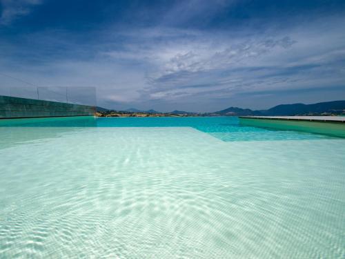 a large pool of blue water with mountains in the background at Serre Alte Landscape Luxury Rooms in Matelica