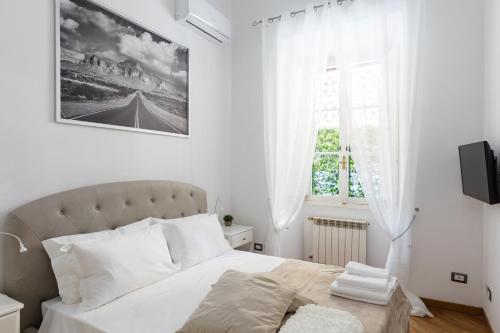 een witte slaapkamer met een bed en een raam bij A World Aparts - 32 Calabria in Rome