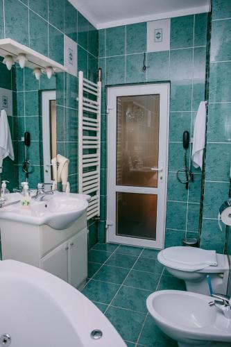 a green tiled bathroom with two sinks and a mirror at Pensiunea Vila Europa in Deva
