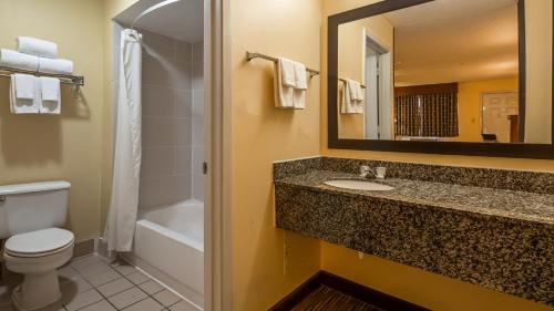 a bathroom with a sink and a toilet and a mirror at Days Inn by Wyndham Round Rock in Round Rock