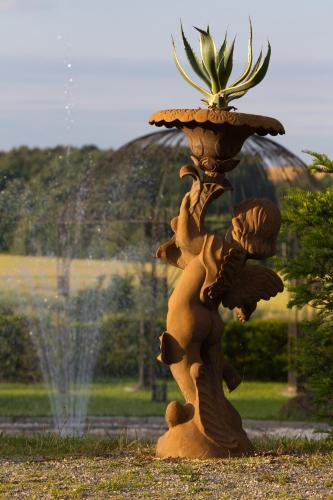 a statue of a person holding a plant in a fountain at Romantik Hotel Schwanefeld & Spa in Meerane