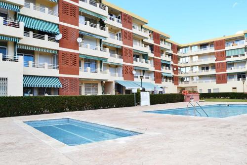 un edificio con piscina di fronte a un edificio di Apartament Les Delícies a Sant Carles de la Ràpita