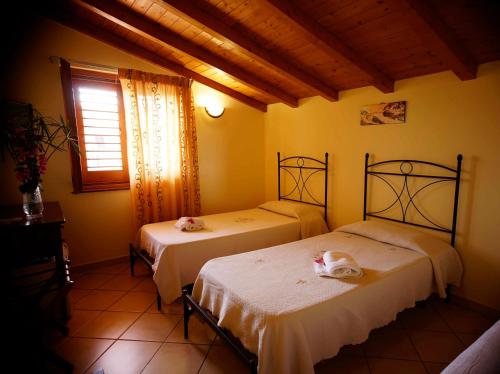 twee bedden in een kamer met gele muren bij B&B Casalotto Inn in Aci SantʼAntonio