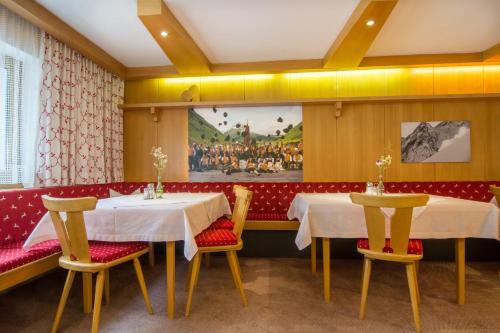 ein Restaurant mit zwei Tischen und Stühlen und einem Gemälde an der Wand in der Unterkunft Frühstückspension Türtscher in Galtür