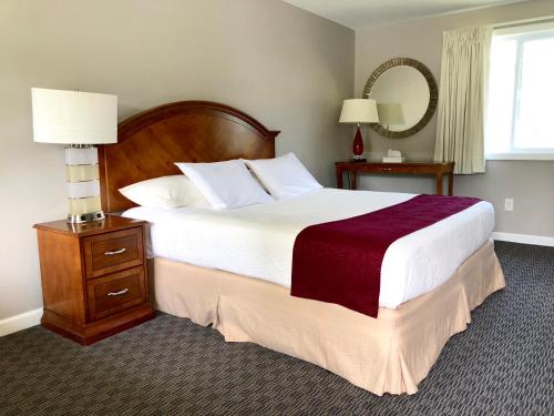 a bedroom with a large bed and a table with a mirror at Inn on The Hill in Lake George