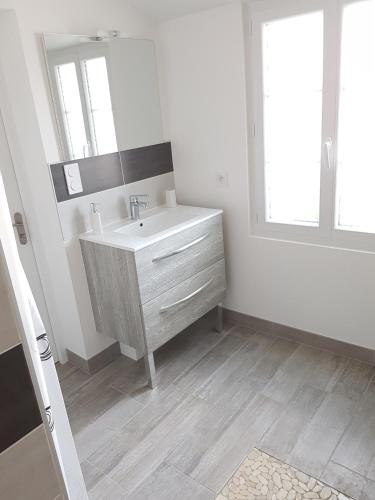 a white bathroom with a sink and a mirror at LA MAISON D'ALIDA in Nueil-sous-Faye