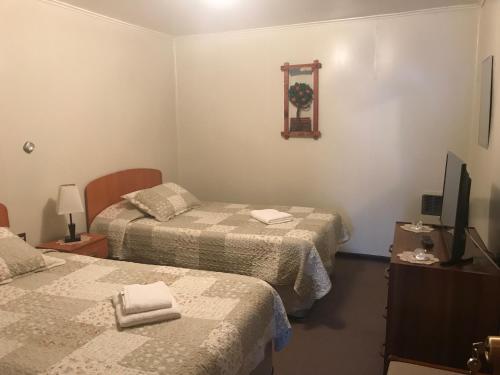 Habitación de hotel con 2 camas y TV en Hospedaje Baquedano, en Puerto Natales