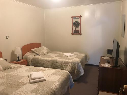 a hotel room with two beds and a television at Hospedaje Baquedano in Puerto Natales