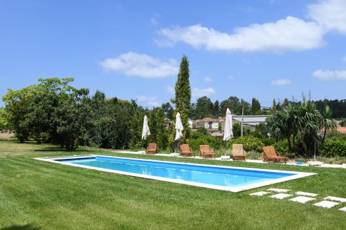 a swimming pool in a yard with chairs and umbrellas at Quinta da Fogueira in Anadia