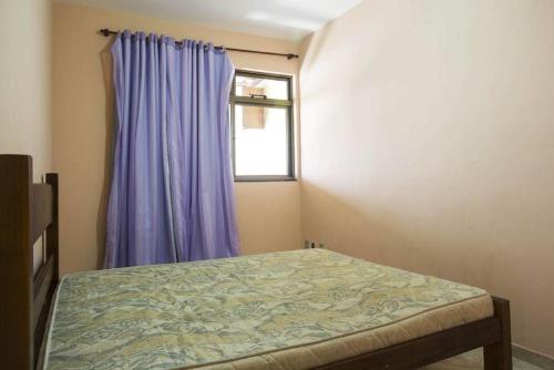 a bedroom with a bed and a window with purple curtains at Edificio caminho do sol in Arraial do Cabo