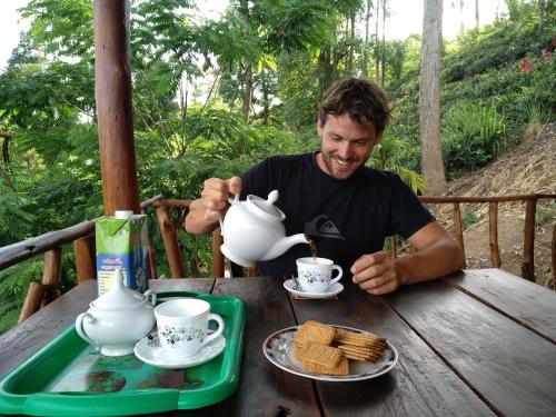 a man sitting at a table with a tea pot at Apurvi Homestay in Ella