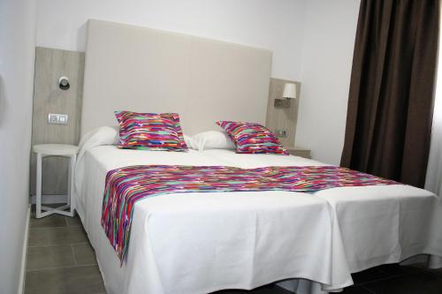 1 dormitorio con cama blanca y almohadas coloridas en Bungalows Islas Paraiso, en Playa del Inglés