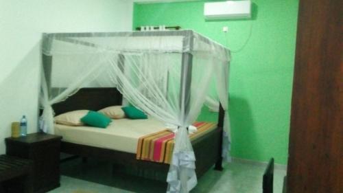 a bed with a canopy in a green room at Akurala Beach Park in Hikkaduwa