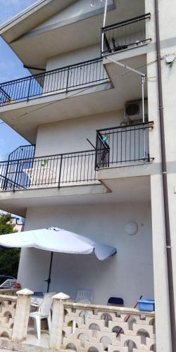 a balcony with an umbrella and a table and chairs at Appartamenti Don Guglie' in Cetraro