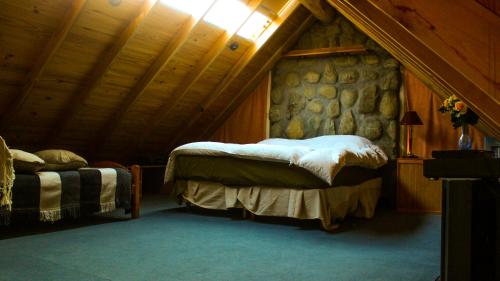 1 dormitorio con 2 camas y pared de piedra en Hospedaje Andorra La Vella en Ushuaia