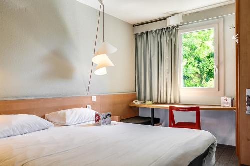 a hotel room with two beds and a desk and a window at ibis Salon de Provence in Salon-de-Provence