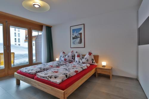 een slaapkamer met een bed en een groot raam bij Ferienwohnung Steinmattstrasse in Zermatt