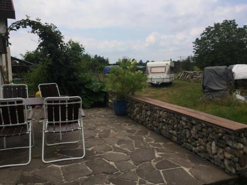 a patio with chairs and a stone wall and a trailer at Schöne Zimmer im Zentrum Leben in Offenburg
