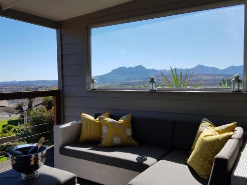 a porch with a couch and a large window at Drommedaris in Gordonʼs Bay