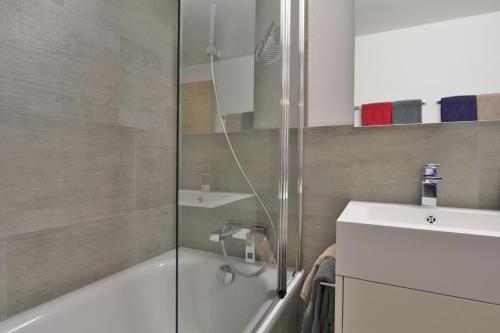 a bathroom with a shower and a tub and a sink at Ferienwohnung Steinmattstrasse in Zermatt