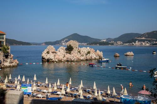 a beach with many umbrellas and boats in the water at Mima Apartments in Sveti Stefan