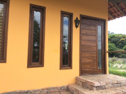 a yellow house with a wooden door and windows at Casa do Capão in Vale do Capao