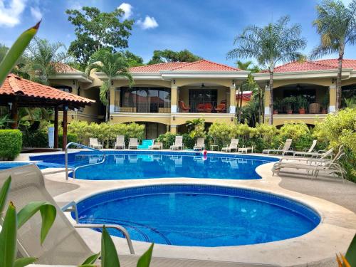 a swimming pool in front of a house at Monte Carlo Luxury Condominiums in Jacó