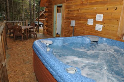 eine Whirlpool-Badewanne in einem Blockhaus in der Unterkunft The Cabins at Pine Haven - Beckley in Beaver