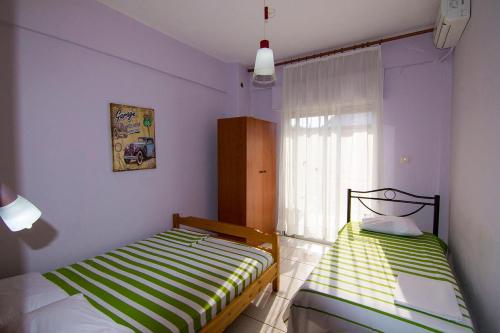 two beds in a room with purple walls and a window at Apartments Anesis Pantazis in Asprovalta