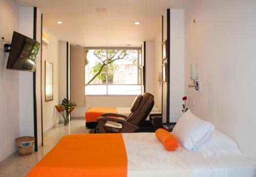 um quarto com uma cama, uma cadeira e uma janela em Hotel Casa Santa Monica Norte em Cali