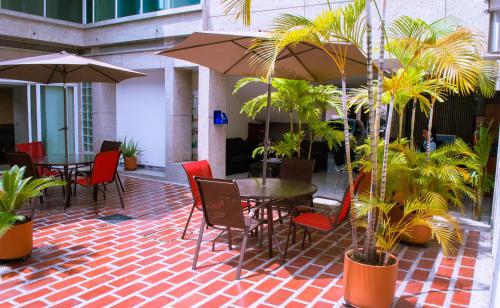 a patio with tables and chairs and palm trees at Hotel Casa Santa Monica Norte in Cali