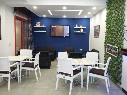 a restaurant with white tables and chairs and a blue wall at London House in Bizerte