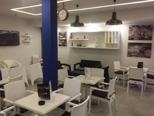 a restaurant with white tables and chairs and a clock at London House in Bizerte