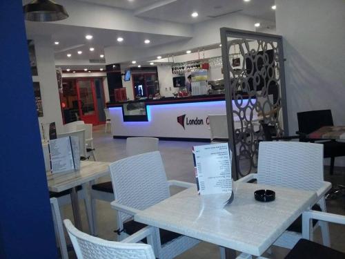 a restaurant with tables and white chairs and a counter at London House in Bizerte