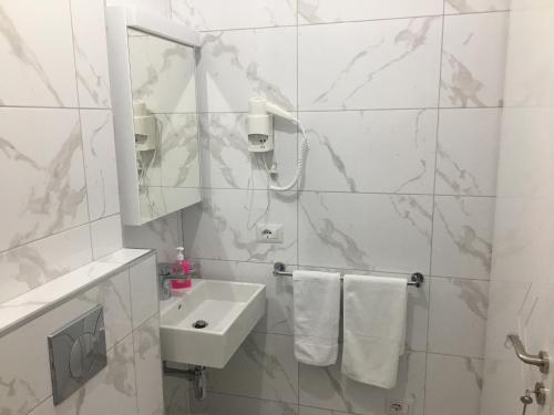 a white bathroom with a sink and a mirror at Villa Orkidea in Sarandë