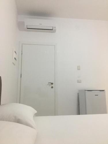 a white bedroom with a bed and a door at Villa Orkidea in Sarandë
